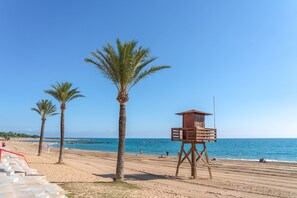 Een strand met palmbomen, een uitkijktoren van de badmeester en een helderblauwe lucht.