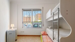 Et værelse med køjeseng, et vindue med tremmer, en lampe og et mindre apparat.