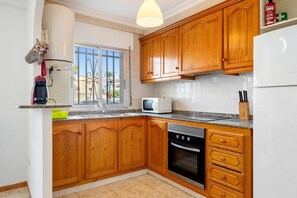 Una cocina con armarios de madera, microondas, estufa y refrigerador.