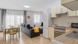 Une cuisine moderne équipée d’un four à micro-ondes, d’un évier et de placards. Un coin repas avec une table et des chaises est également disponible.