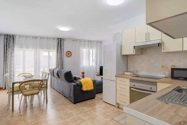 A modern kitchen with a microwave, sink, and cabinets. There is a dining area with a table and chairs.