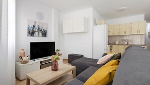 Un salon moderne avec un canapé, un téléviseur et une petite table sur laquelle est posé un vase.