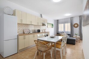 A modern kitchen with a dining area, white cabinets, and a dining table with chairs.