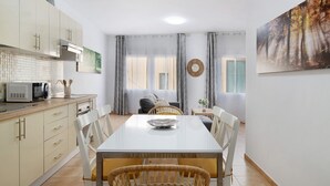 Une cuisine moderne avec des meubles blancs et un coin repas comprenant une table et des chaises blanches.