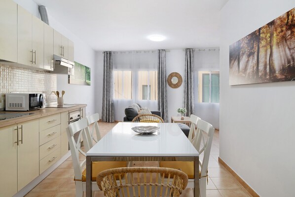 A modern kitchen with white cabinets and a dining area with a white table and chairs.