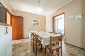 Un comedor con una mesa, sillas, un armario y una ventana.