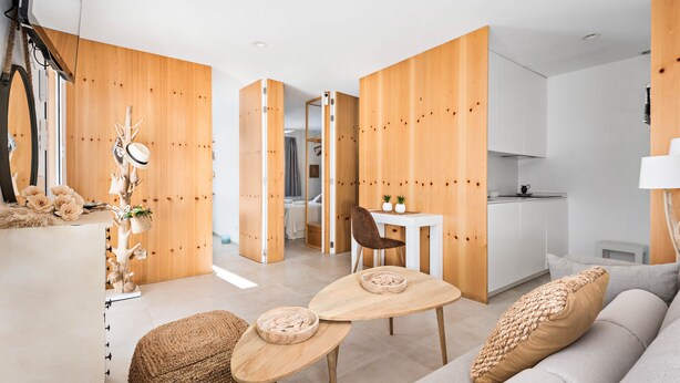 A modern living room with a sofa, coffee table, and a dining area with a chair.