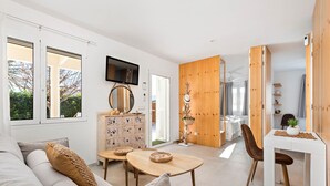 A modern living room with a sofa, coffee table, and a dining area with a wooden cabinet and TV.