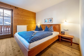 Un dormitorio con paneles de madera, una cama, un banco y un radiador.