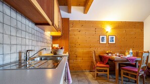 Une cuisine avec un mur en bois, une table à manger avec des chaises et un mur recouvert de carreaux.