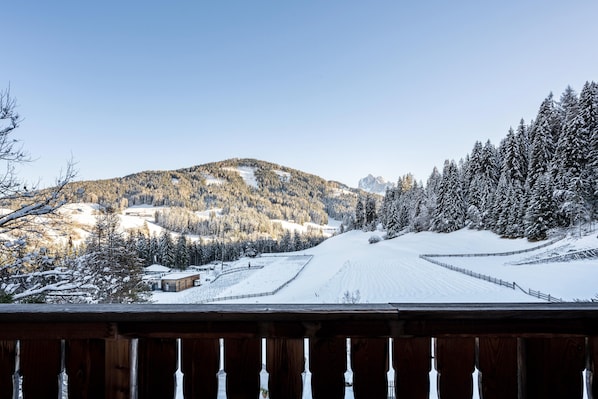 A snowy landscape with a wooden deck and a view of a snow-covered road leading to a mountain.