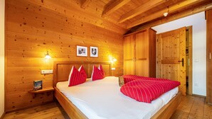 Une pièce en bois avec un lit, des murs en bois et une porte.