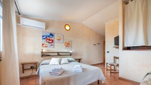 Une chambre d’hôtel avec un lit, une table de chevet, une télévision et des œuvres d’art accrochées au mur.