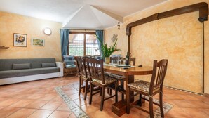 Un coin repas avec une table et des chaises en bois, un canapé et une fenêtre avec des rideaux.
