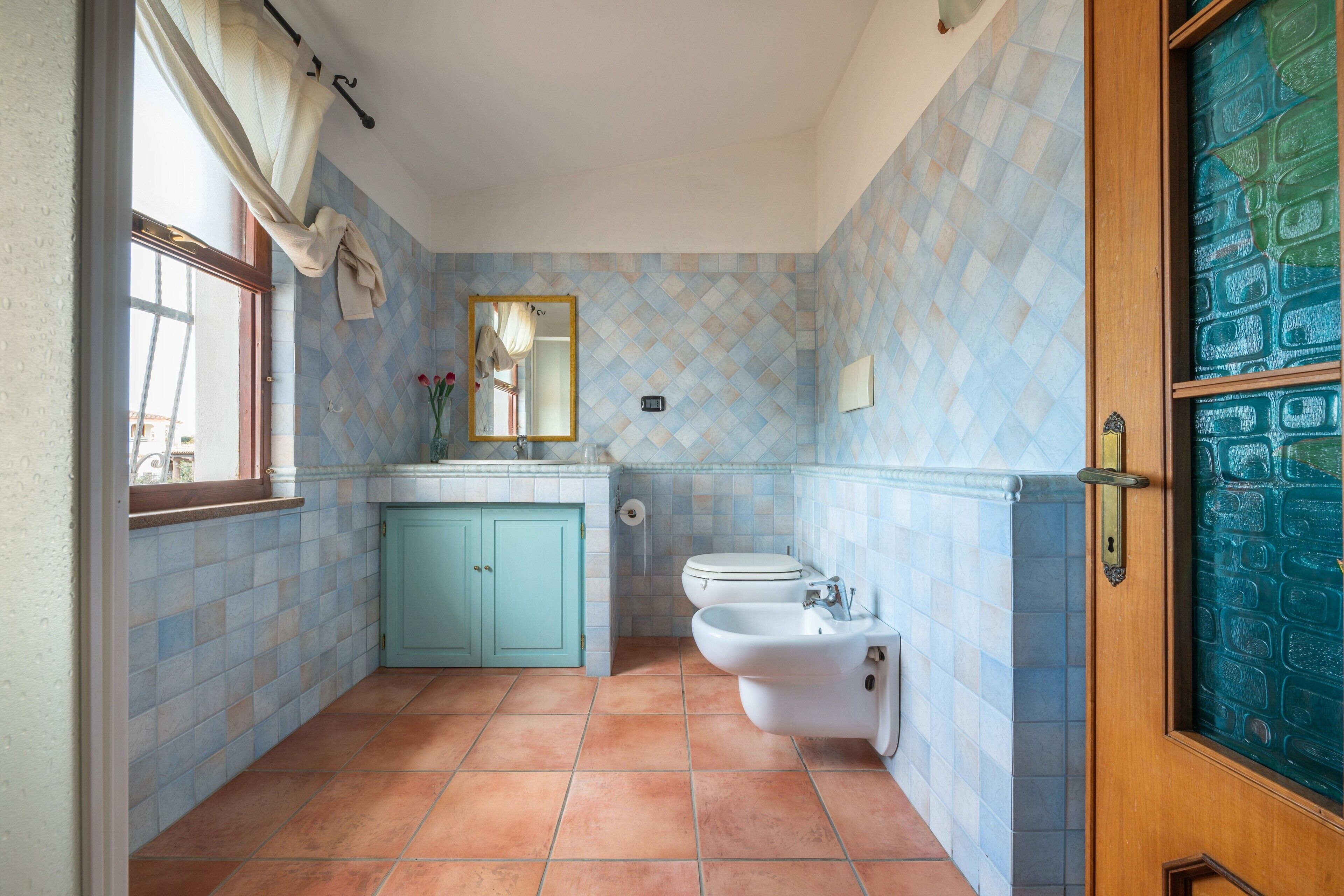 Une salle de bain avec une fenêtre, un lavabo, un bidet et des toilettes.