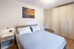 Makuuhuone, jossa on sänky, yöpöydät, seinälle ripustettu taulu ja vaatekaappi.
