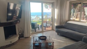 A living room with a flat-screen TV, a grey sofa, a wooden coffee table, and a view of the sea through large glass doors. - Villa 'Costa Dei Monaci Villas - Tropea' with Sea View, Wi-Fi and Air Conditioning (Costa dei Monaci)