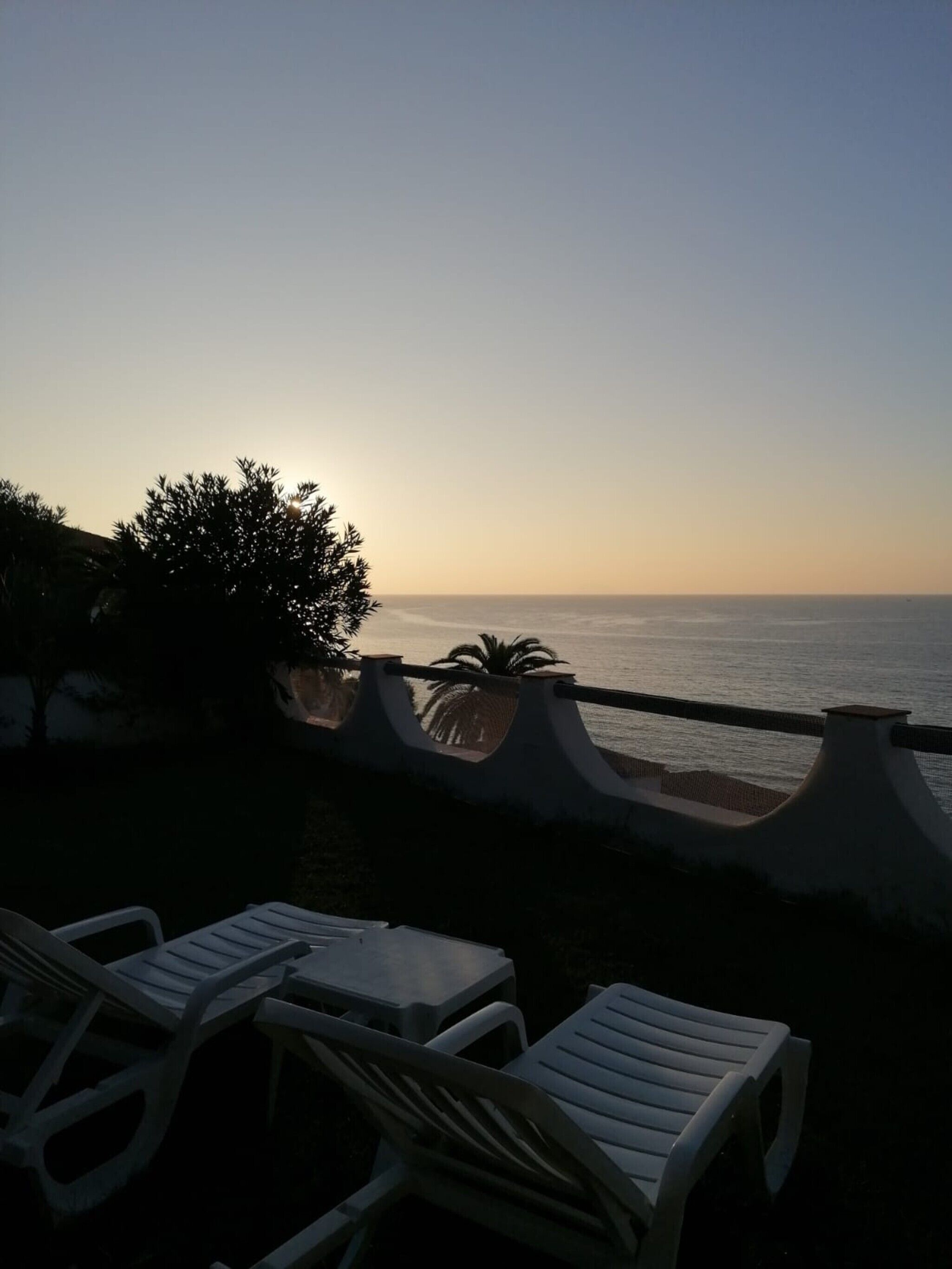 Vista sul mare con ringhiera, sedie e tavolo.