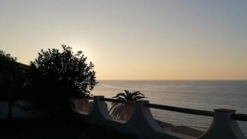 Blick auf das Meer mit Geländer, Stühlen und Tisch.