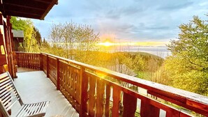 Un balcon avec des balustrades en bois, un banc et une table ronde.