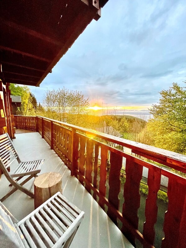 A balcony with wooden railings, a bench, and a round table.