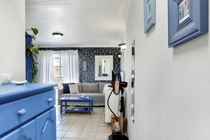 A room with a blue dresser, a gray sofa, a small table, and a fan.