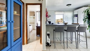 Een moderne keuken met een bar, een blauwe kast en een witte koelkast.