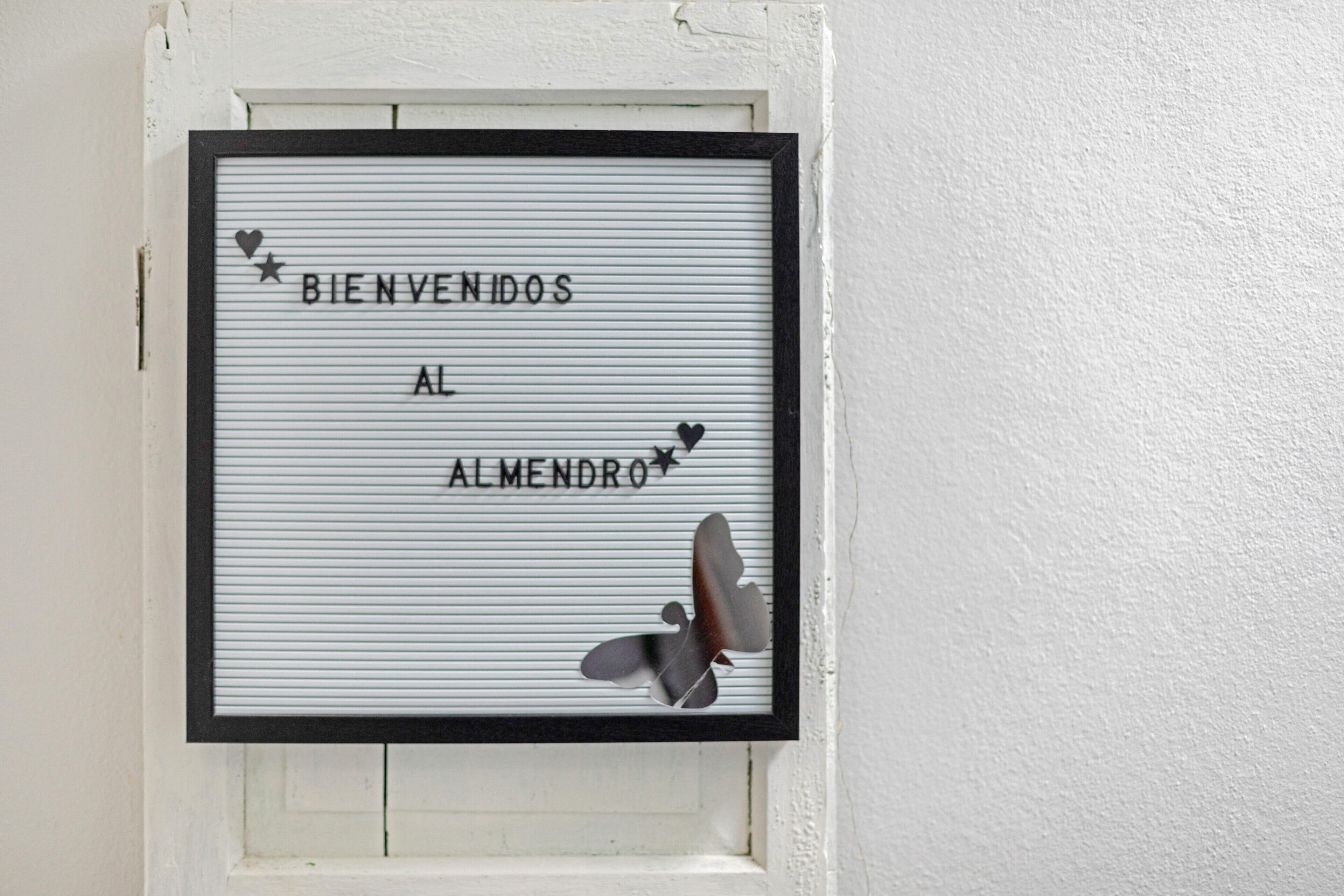 Letrero de bienvenida enmarco con la inscripción 'BIENVENIDOS AL ALMENDRO' y detalles decorativos.