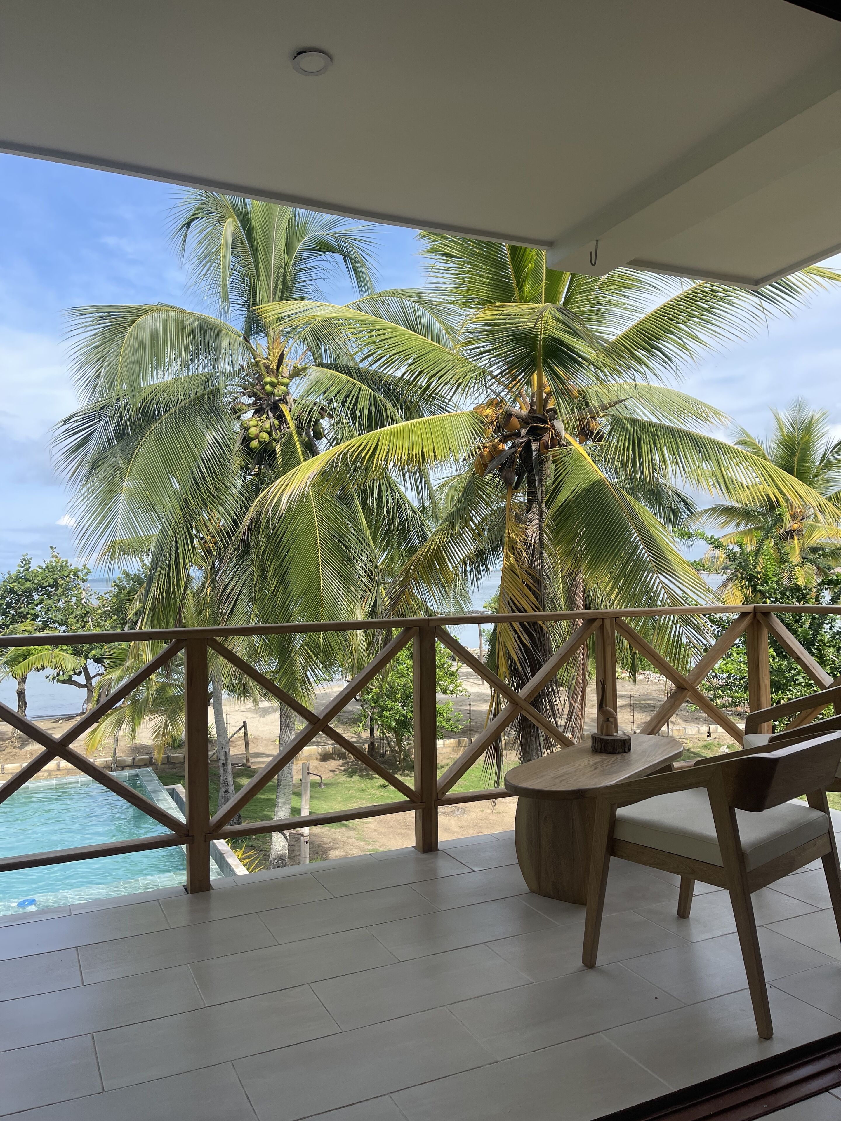 A balcony with a view of a pool and palm trees.