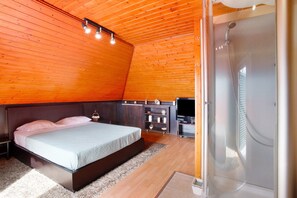 Une chambre avec un lit, une télévision, un plafond en bois et une douche.