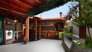 Ein überdachter Patio-Bereich mit Waschmaschine, Esstisch und einem durchgehenden Durchgang zur Küche.