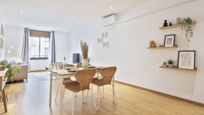 Un comedor moderno con una mesa de madera y sillas de mimbre, una planta en maceta y un aire acondicionado instalado en la pared.