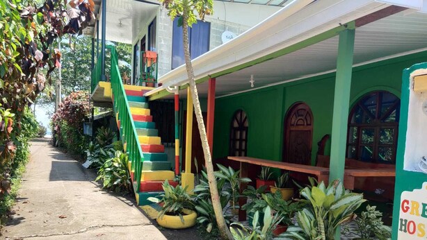 A colorful building with a green exterior, a yellow staircase, and potted plants. - Green House Casa de Playa Tortuguero (Colorado)