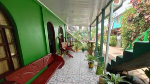A covered outdoor area with a tiled floor, green walls, and red benches. - Green House Casa de Playa Tortuguero (Colorado)