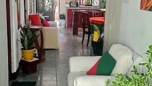 A spacious living area with a white sofa, a dining table, and various potted plants. - Green House Casa de Playa Tortuguero (Colorado)
