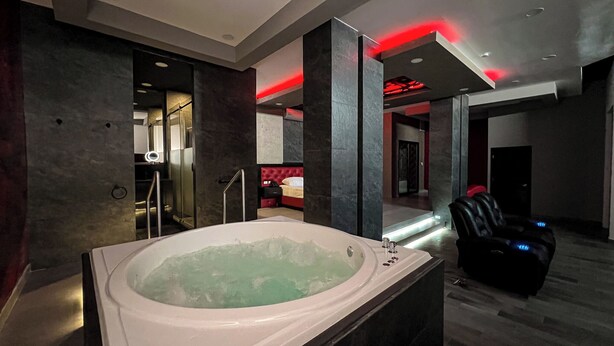 Un baño moderno con una bañera grande, un sillón de masaje y un techo iluminado con luz roja.