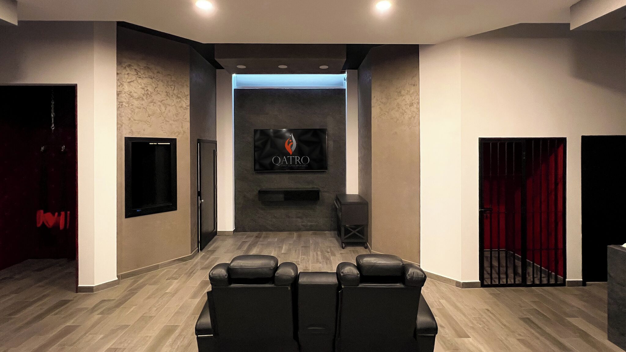 Een receptiegedeelte met een flatscreen-tv waarop het QATRO logo staat, een receptiebalie en drie zwarte lederen fauteuils.
