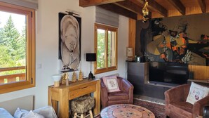 A cozy living room with a fireplace, leather armchairs, a round coffee table, and a large painting on the wall. - Warm chalet for 6 people, Saint-Chaffrey (Saint-Chaffrey)