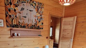 A bedroom with a large bed, a wooden ceiling, a hanging light fixture, and a colorful wall mural. - Warm chalet for 6 people, Saint-Chaffrey (Saint-Chaffrey)