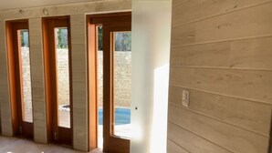 Ein Korridor mit Holzwandverkleidung, Marmorboden und mehreren Türen zu Außenbereichen.
