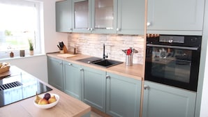 A modern kitchen with light green cabinets, a black sink, and a built-in oven.
