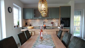 A modern kitchen with green cabinets, a wooden island, and a dining table set for six.