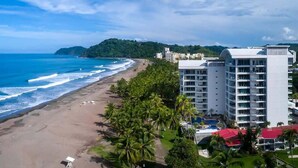 Un hotel frente al mar con vista a la playa, varios pisos y zona de piscina.