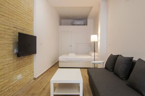 A compact hotel room with a bed, a sofa, a small table, and a TV mounted on the wall. - VLC HOST - Fray Pedro E (Valencia)