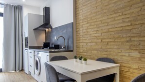 Une cuisine moderne dotée d’un lave-linge encastré, d’un coin repas avec une table et des chaises, et d’un mur en briques.
