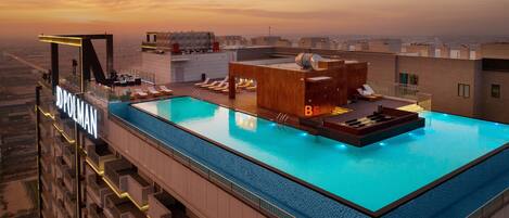 A rooftop pool with a view of the city at sunset.