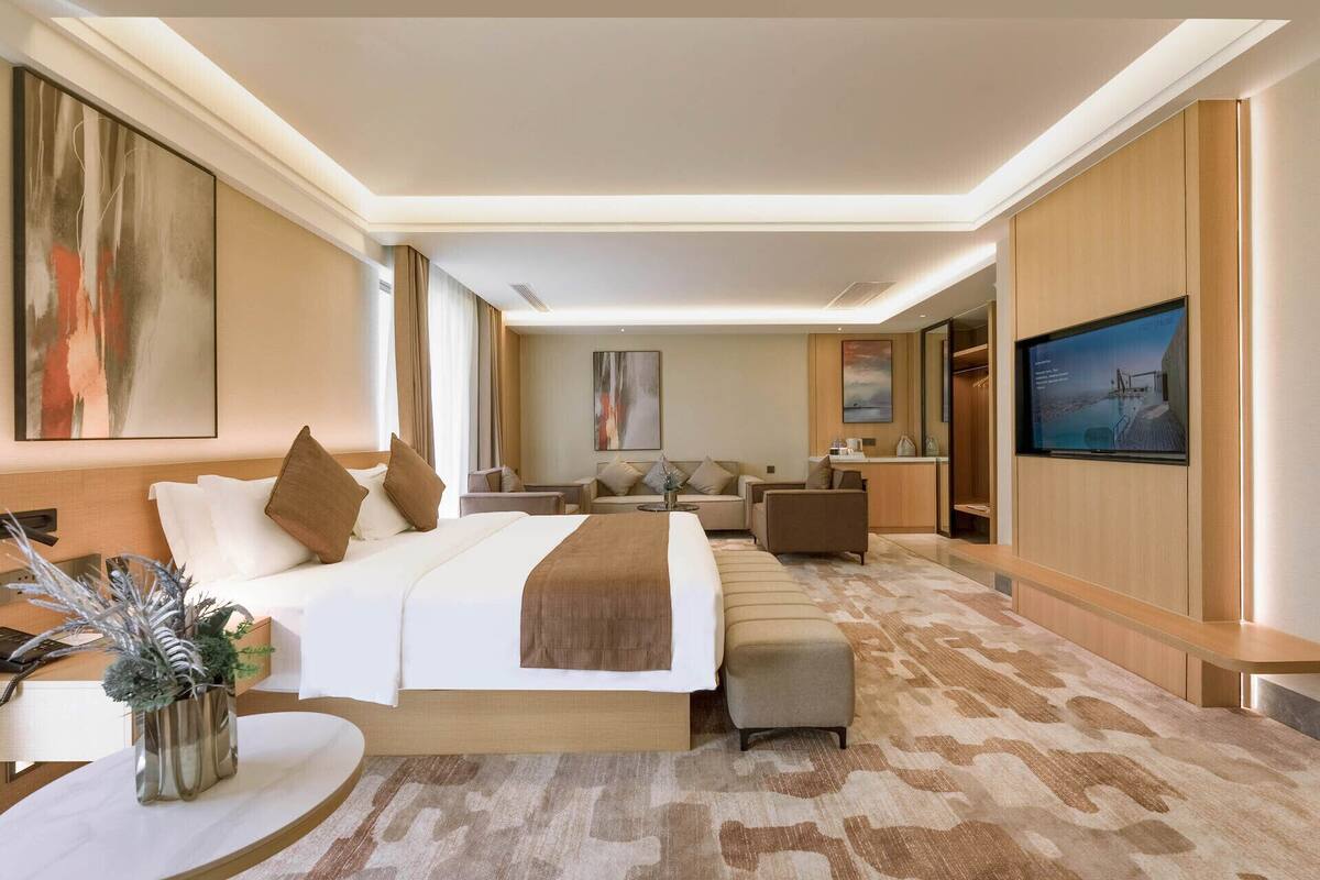 A hotel room with a large bed, a sofa, a TV, and a desk.