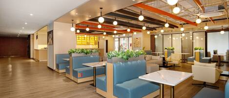 A modern interior with seating areas, tables, and a kitchen in the background.