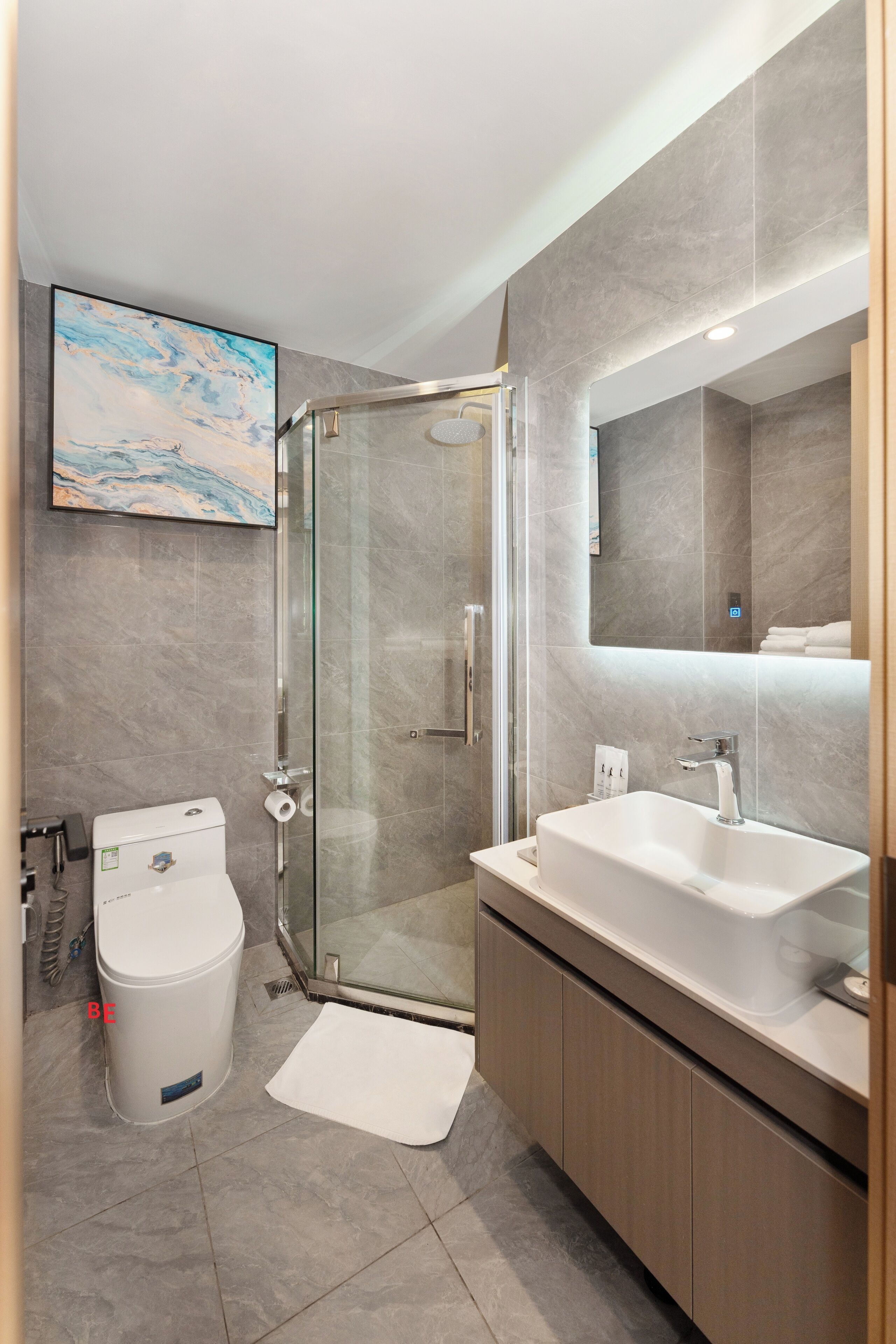 Un bagno moderno con cabina doccia in vetro, lavandino bianco e uno specchio grande.