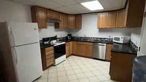 A kitchen with wooden cabinets, a refrigerator, a stove, a microwave, and a water dispenser. - Spacious 2 Bedroom Apartment downtown Winifred,8 miles from the Missouri Breaks! (Winifred)